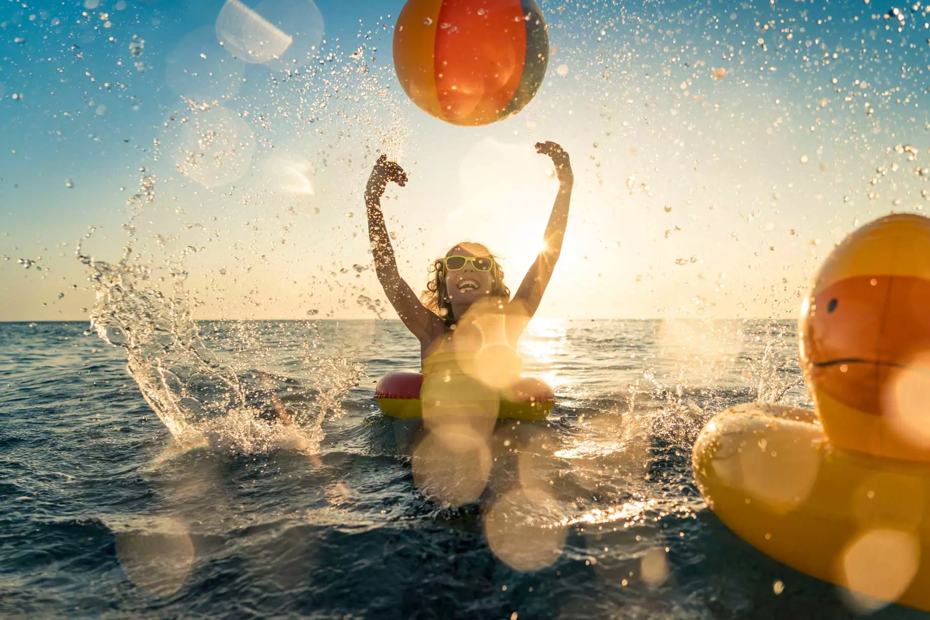 Un enfant joue dans l'eau sur fond de coucher de soleil