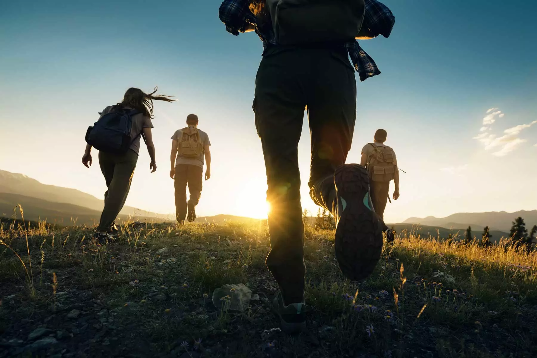 Un groupe d'amis font une randonnée sur fond de coucher de soleil