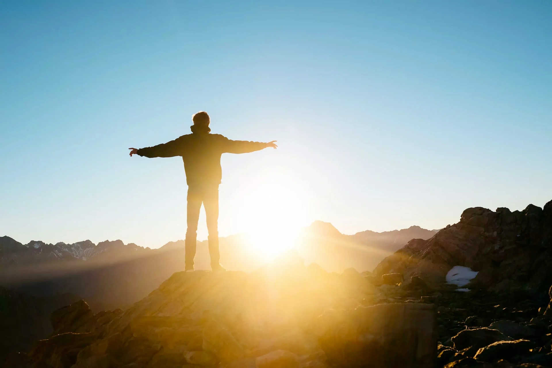 Un adulte se tient debout face à un coucher de soleil