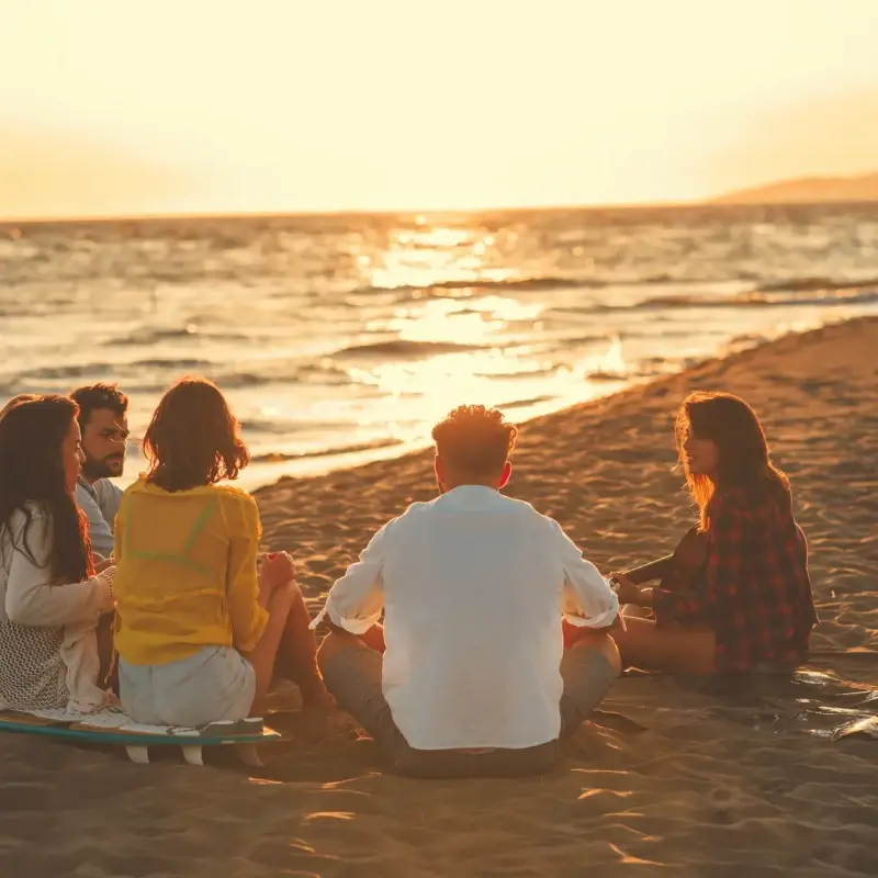 Des amis à plage face au coucher de soleil